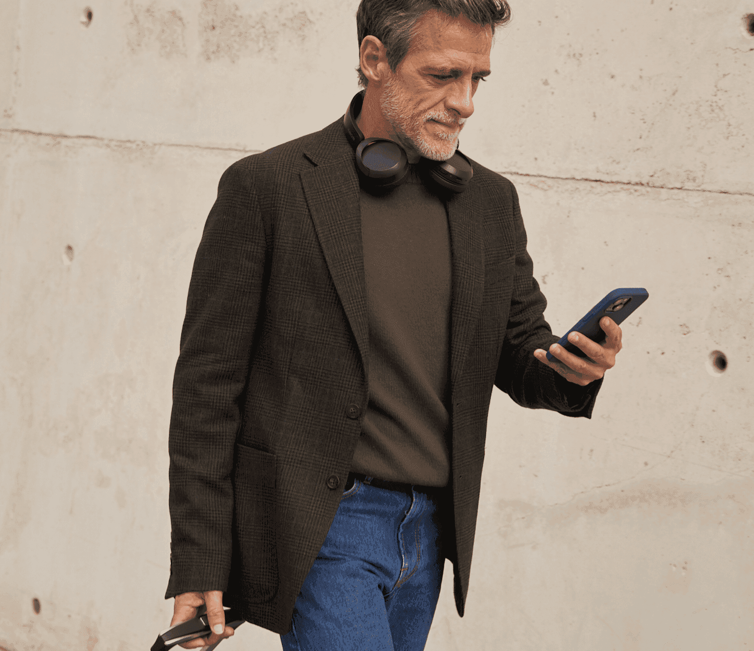 Viajero de negocios con auriculares consultando el móvil