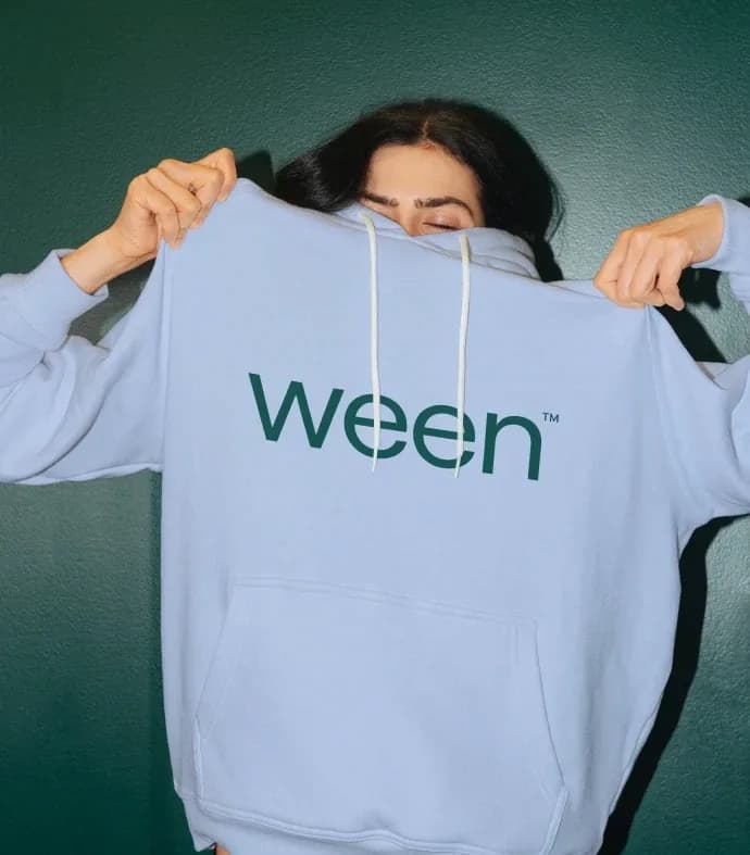 Persona sosteniendo una sudadera con el logo de Ween